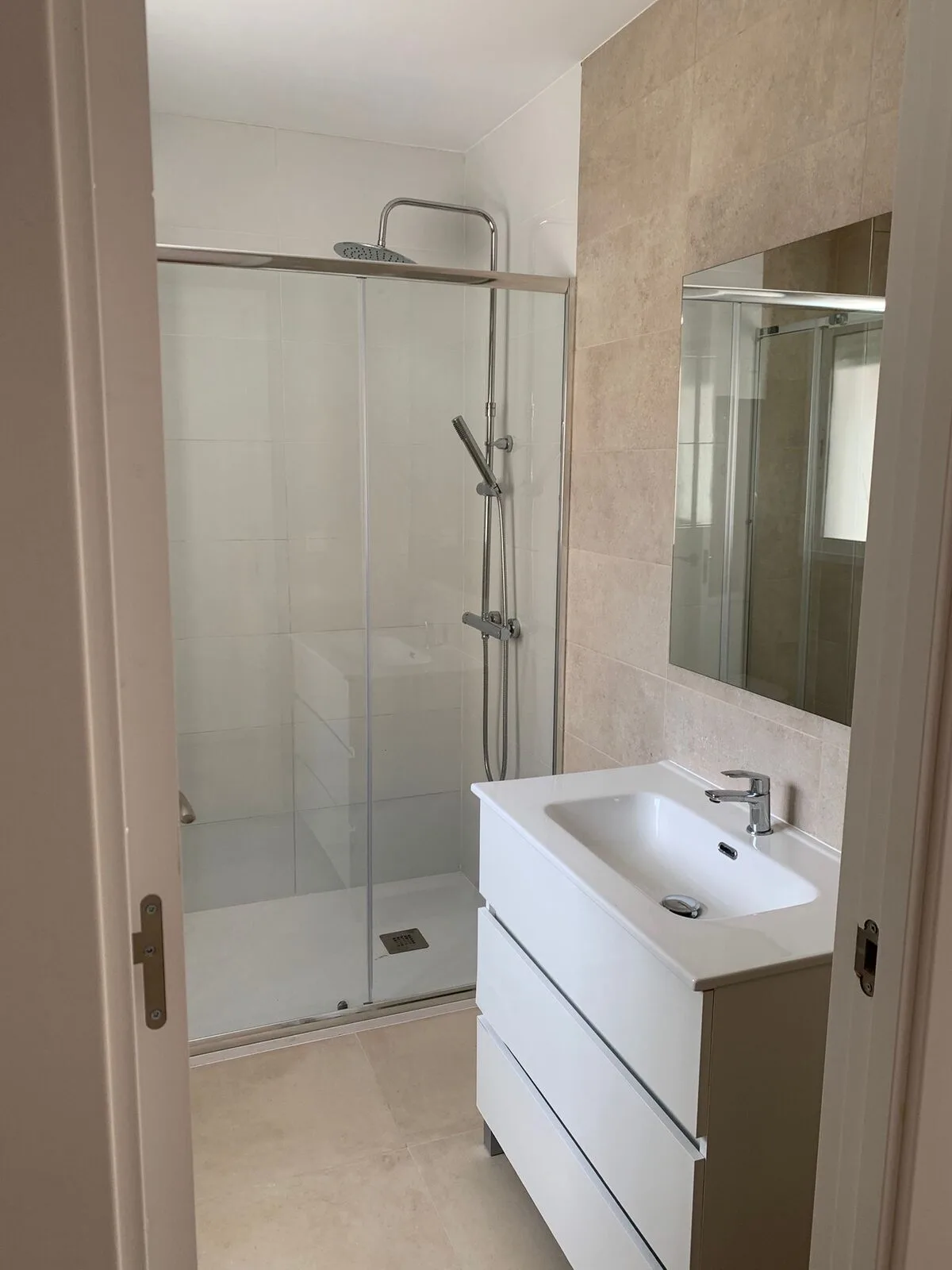 El mismo tipo de baño terminado, con ducha, mampara y mueble suspendido
